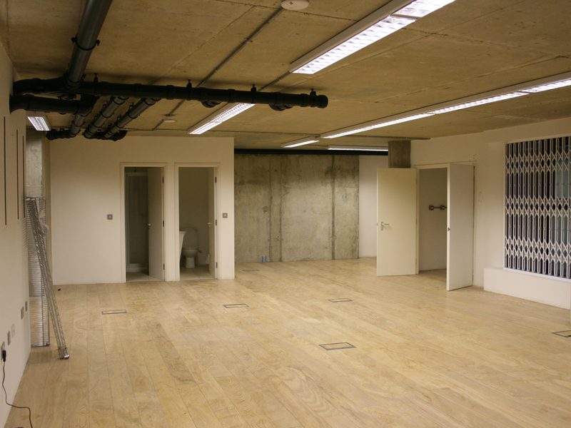 A bright open room with freshly laid pale wood flooring and white walls