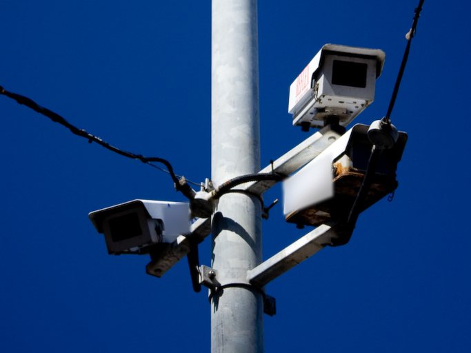Security cameras mounted on a metal pole against a deep blue sky